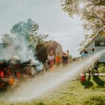 Firefighter showcases safety techniques on a controlled fire at a community event in the park.