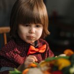 Adorable child enjoying fresh vegetables at the dinner table.